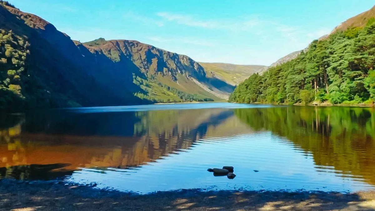 Glendalough round tower and lakes on a day among the vacation tours of Ireland from Dublin